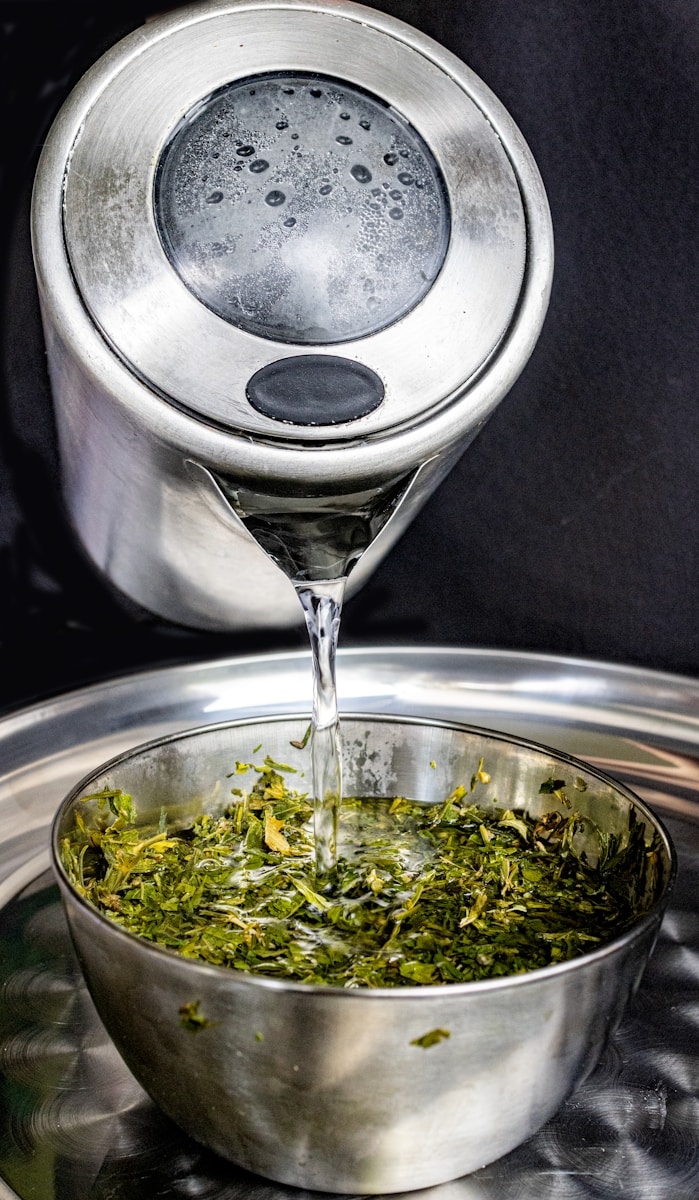 A silver bowl filled with green tea on top of a metal tray