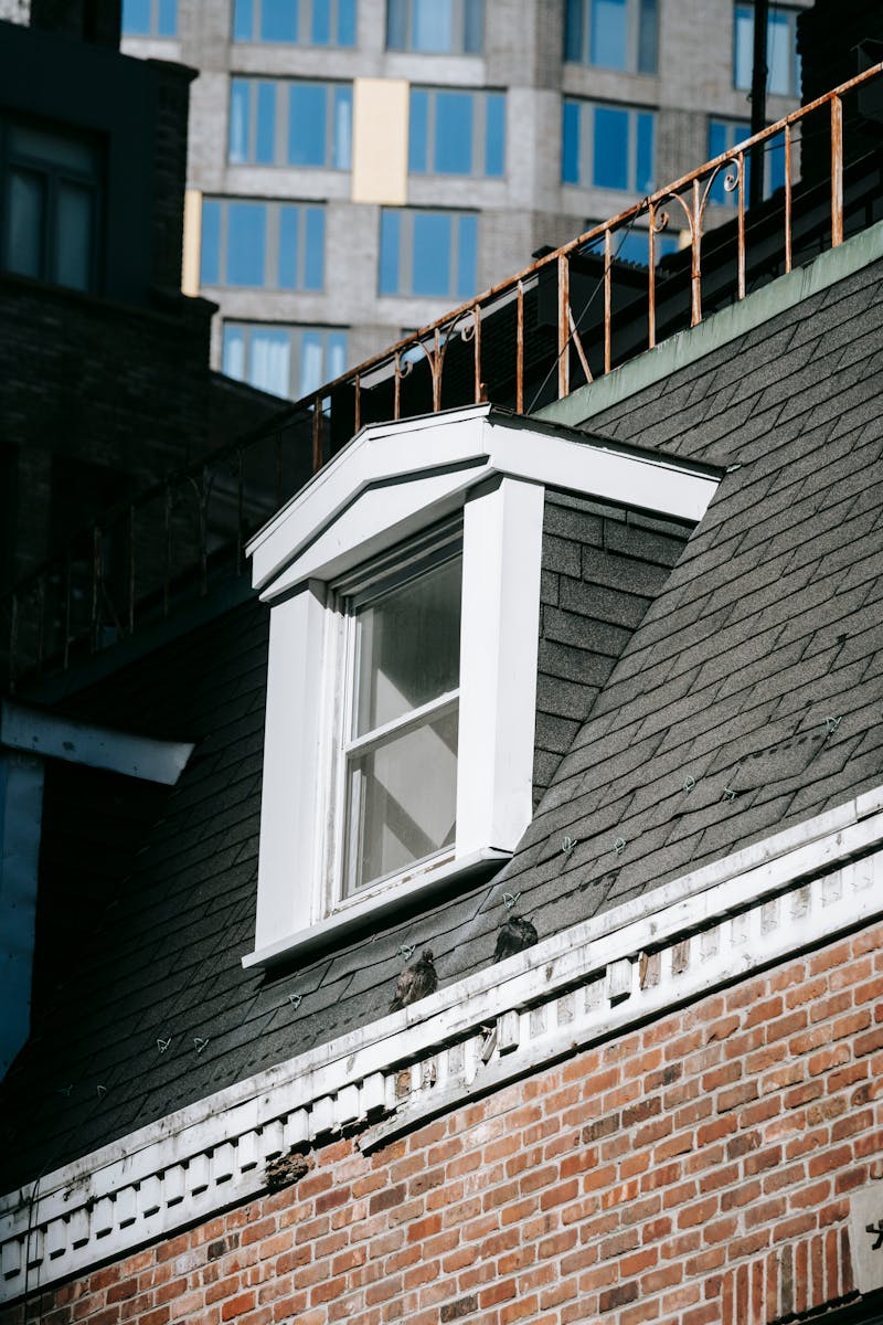 From below exterior fragment of aged residential house with brick walls and attic window in city